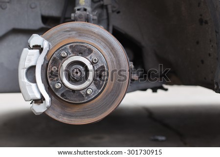 Front disc brake on car in process of new tire replacement