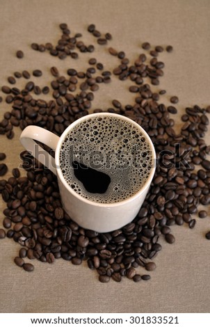 White ceramic coffee mug with coffee beans on cloth sack