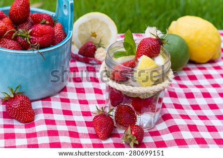 Homemade strawberry lemonade with mint and fruits around.