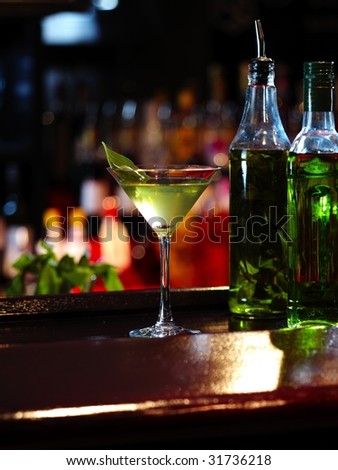 green mint cocktail and two transparent bottles on the wooden bar
