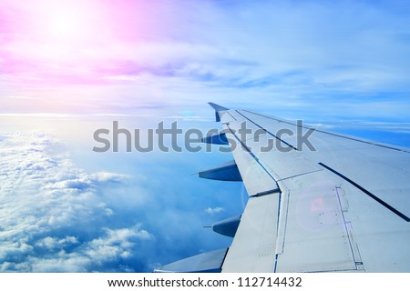 Wing of an airplane flying above the clouds. people look at the sky from the window of the plane, using air transport to travel. back light sun beam
