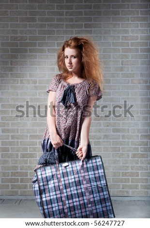 Tired redhaired woman with shopping bag.  brick wall as background.