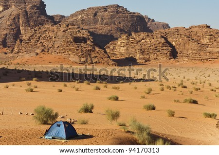 Lone tent in the Wadi Rum UNESCO World Heritage desert area. Long shadow from a towering peak.