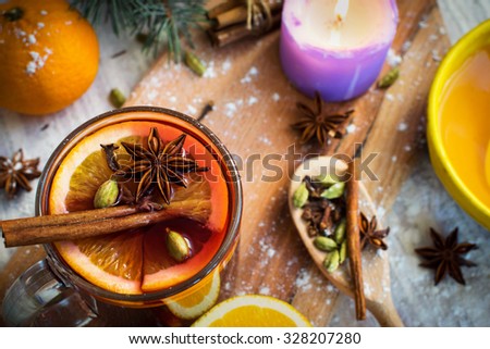 Hot red mulled wine with honey, orange slices, ginger, cardamom, cloves, anise and cinnamon sticks. Christmas decorations, close up.