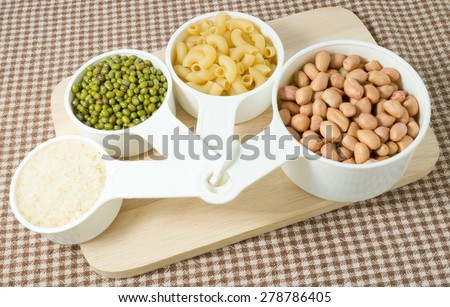 Foods High in Carbohydrate, Raw Pasta, Rice, Peanuts and Mung Beans in Plastic Measuring Cups.