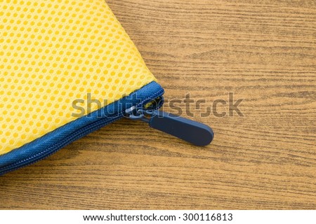 Yellow Pocket Bag and Blue Zipper on A Wooden Table with Copy Space for Text Decorated.