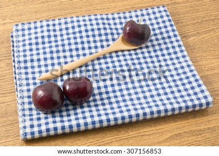 Fresh Fruits, Three Red Plums A Very Good Source of Vitamin C on Blue and White Checked Towel.