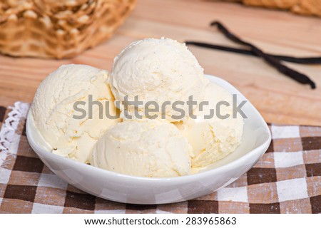 Vanilla ice cream in white bowl with waffles on the wooden background