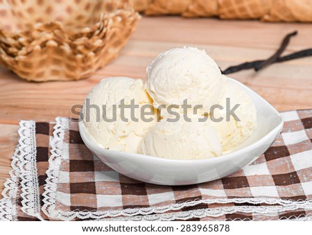 Vanilla ice cream in white bowl with waffles on the wooden background