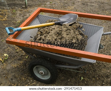 Steel modern cart, sieve for ground and metal shovel in the yard