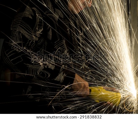 Guy in protective goggles drills metal grinder and sparks jump out everywhere