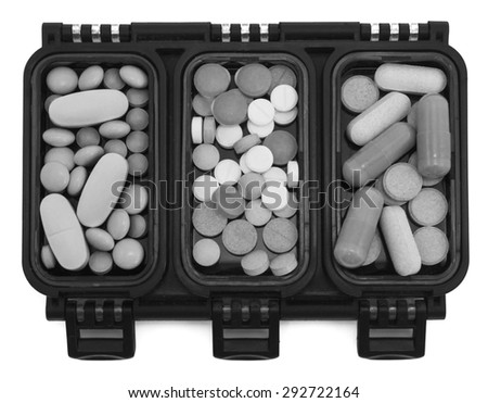 Multi-colored pills in green box organizer black and white isolated on white