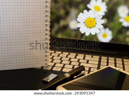 Office workplace with notebook, smart phone, pen, flash drive and wordpad with flowers background