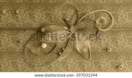 Gold horizontal handmade greeting decoration with shiny beads, embroidery, silver thread in form of flower and butterfly on background of vintage fabric