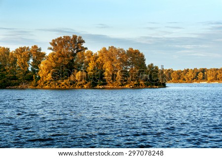 Panorama of river, forest, bushes, grass and sky in autumn