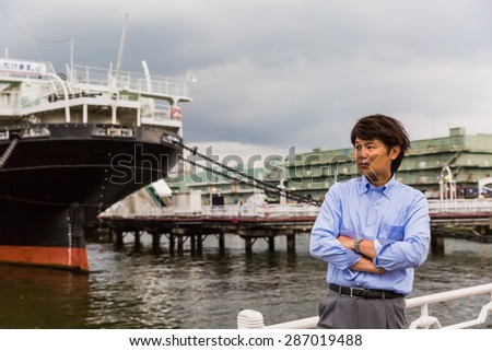 A Japanese business man in front of a cargo ship