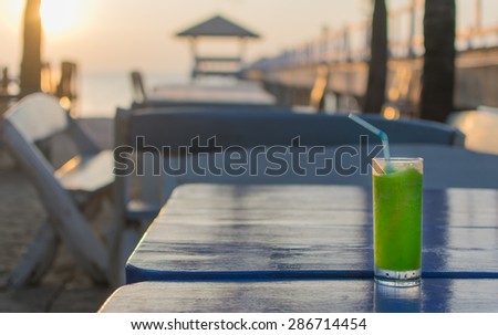 Kiwi smoothie drink on the wooden table at the sea with sunset.