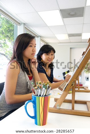 Artists completing art work or student with art teacher