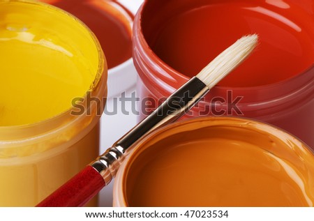Jars of rich, earth colored acrylic artist paint and bristle paintbrush