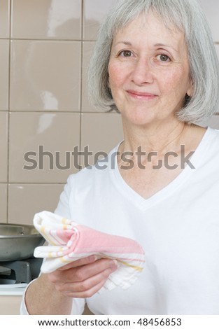 Senior woman standing in front of the stove smiling.