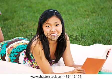 Young woman student reading on a blanket outdoors