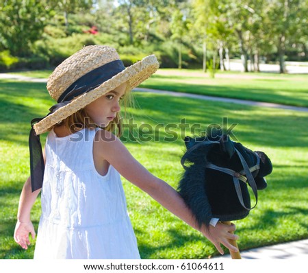 Little girl wearing straw hat and holding her toy pony