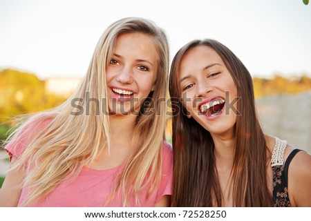 Teen girl best friends laughing and having fun outdoors