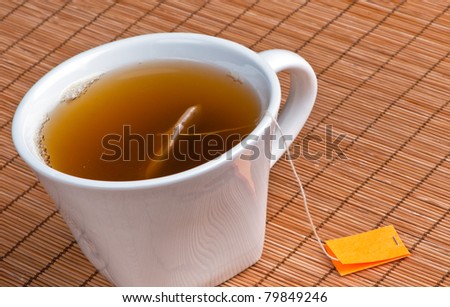 Hot tea in cup with bag on place mat and blank label