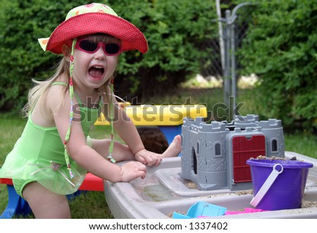 Young toddler in swimsuit having fun playing with summer toys.