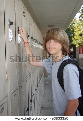 Cute middle school teen opening his school locker.