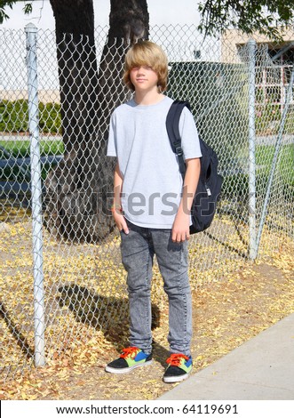 stock photo Cute teen boy standing in front of chain link fence near 