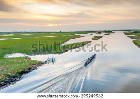 person on a boat in a narrow body of water and sunset in thailand