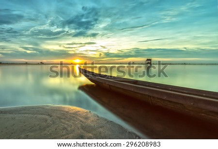 The boat speeding toward the sun as if to hold back the \
light at sunset while the sun shines bright yellow rays radiating below the surface smooth like smoke.