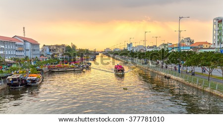 Ho Chi Minh City, Vietnam - February 6th, 2016: Boat on river carry flowers to sell in afternoon sun rays  beautiful, boat parked left busy selling flowers fun spring day in Ho Chi Minh city, Vietnam