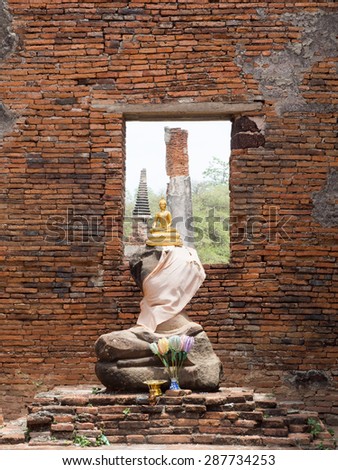 Sitting position buddha golden statue sitting on buddha statues without head ,arm and old Brick in Ayutthaya historical park, Ayutthaya , Thailand.