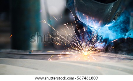 Industrial concept: worker in helmet repair detail in car auto service, close uptelephoto