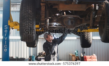 Car service - a mechanic checks the suspension of SUV, wide angle