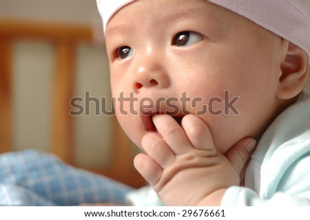 it is a cute chinese baby, eating his hand. he is 4 months.