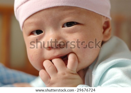 it is a cute chinese baby, eating his hand. he is 4 months.