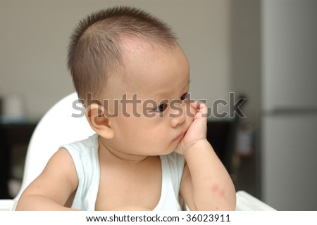 it is a cute chinese baby, he is 8 months old. a  thinking something pose.