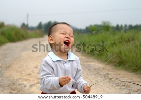 it is a laughing chinese baby on the countryside road.