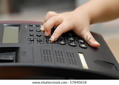 A boy hand is on the pone keyboard, he is dialing the phone number for making a call.