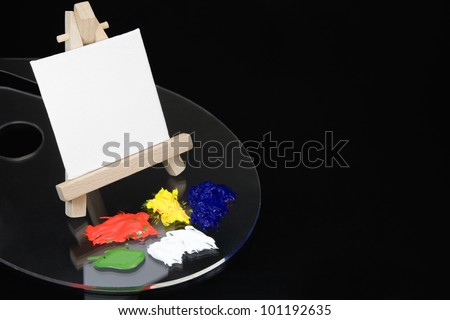 Mini Easel and blank white canvas on a kidney paint palette with acrylic paints