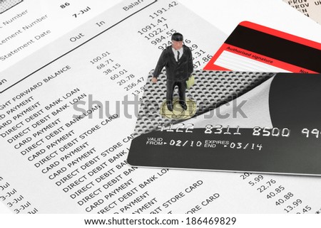 Miniature Businessman Figurine on Credit Cards and Bank Statements