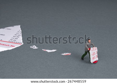 bank statement torn into little pieces and a plastic workman figurine with a torn section of bank statement on a trolley.