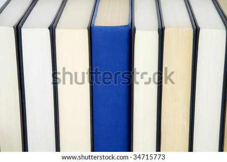 Group of books in a row and one book standing out from others with spine showing.