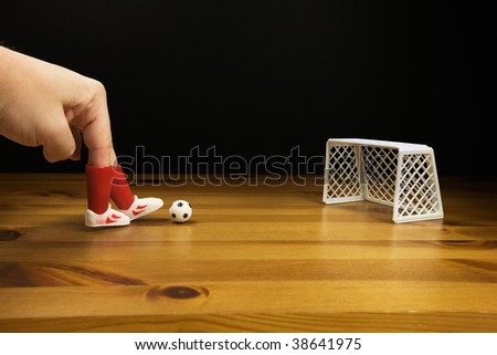 A persons Fingers in Plastic Football Boots Playing Table top Football on a wooden table,