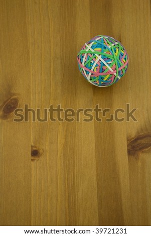 Elevated View of a Multi coloured Rubber band ball on a wooden table