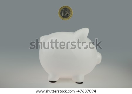 White Piggy bank With One Euro Coin falling from above and heading for the money slot,