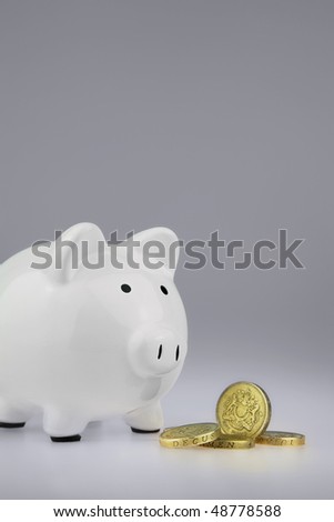 White Piggy bank With British One Pound Coins in front of money box,